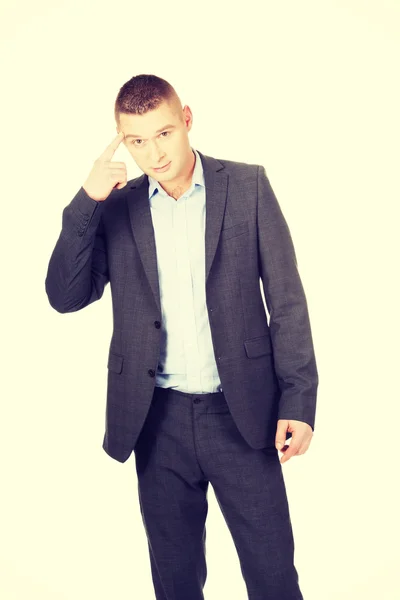 Businessman gesturing with finger against temple — Stock Photo, Image