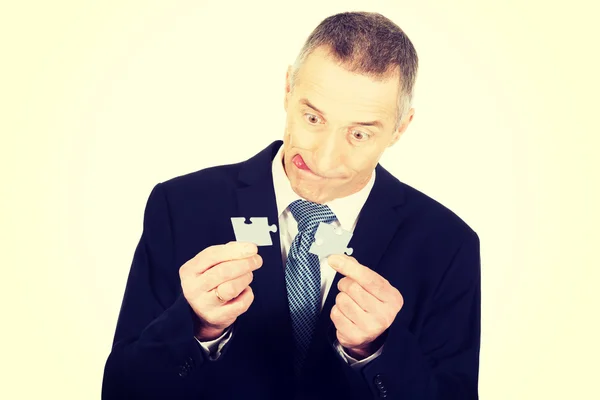 Empresario mostrando piezas del rompecabezas . — Foto de Stock