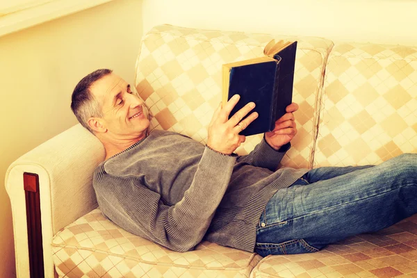 Homem maduro lendo um livro em casa — Fotografia de Stock