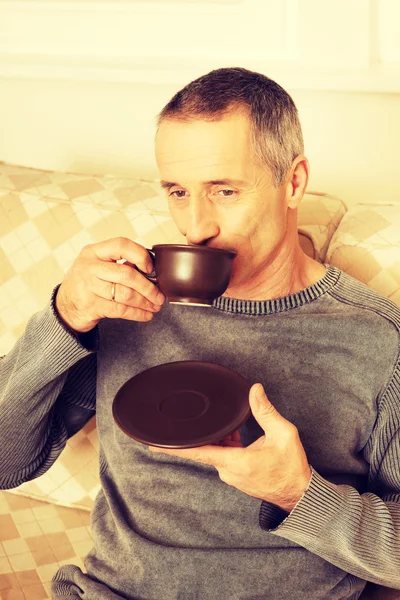 Casual man sitting on couch drinking coffee — Stock Photo, Image