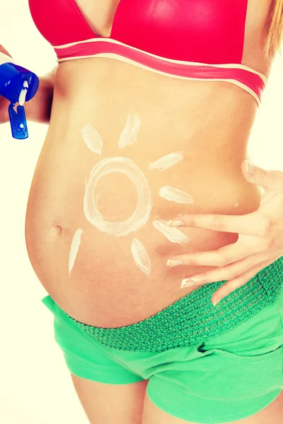 Mujer aplicando crema solar en el vientre — Foto de Stock