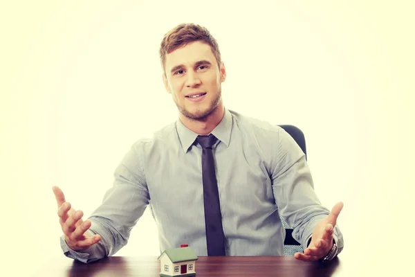 Empresário com modelo de casa por uma mesa . — Fotografia de Stock