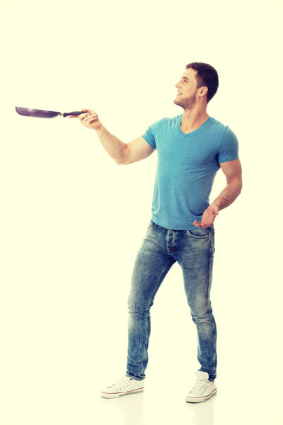 Muscular man holding frying pan.