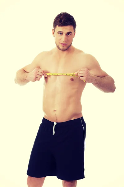 Мускулистый мужчина измеряет грудь . — стоковое фото