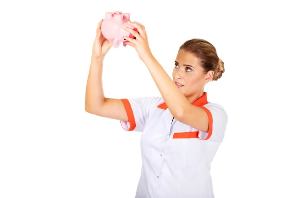 Young female doctor or nurse holding a piggybank — Stock Photo, Image