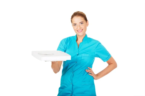 Młody lekarz lub pielęgniarka trzyma wagę — Zdjęcie stockowe