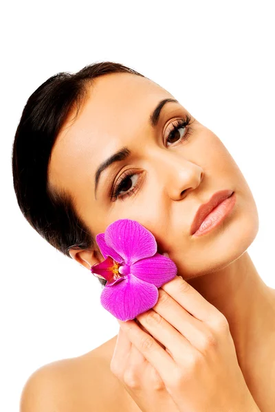 Женщина с фиолетовым лепестком орхидеи у лица — стоковое фото