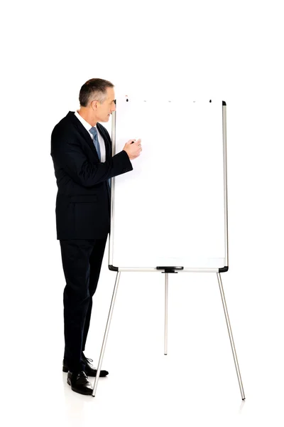 Male executive writing on a flipchart — Stock Photo, Image