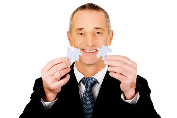 Businessman trying to connect puzzle pieces. — Stock Photo, Image