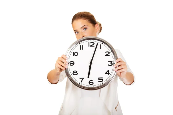 Businesswoman covering face with clock Stock Picture