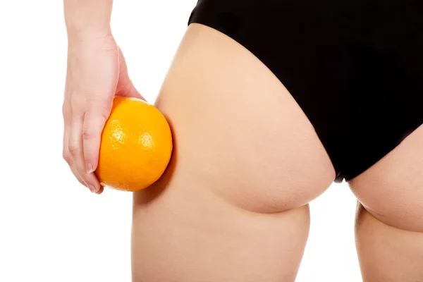 Female buttocks and orange in hand. — Stock Photo, Image