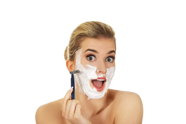 Mladá šokovaná žena holení její obličej — Stock fotografie