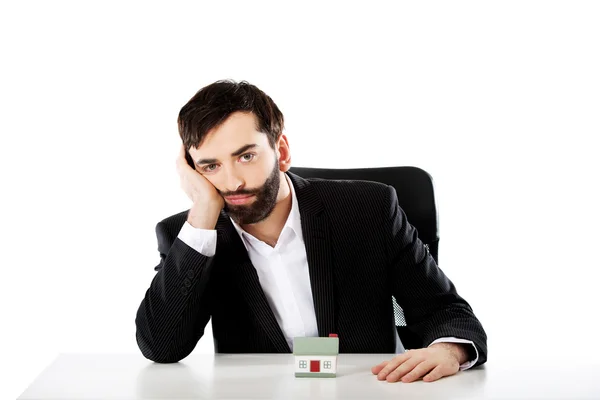 Zakenman met een mini huis in het kantoor. — Stockfoto