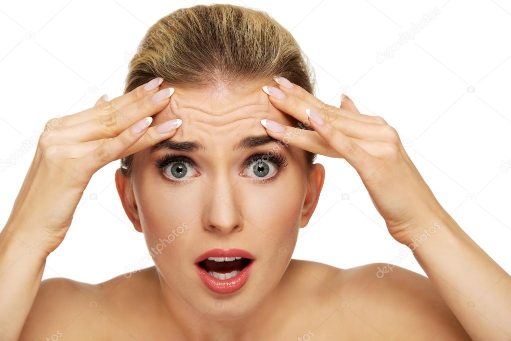 Woman checking wrinkles on her forehead