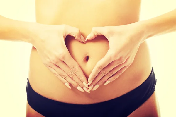 Woman making heart shape on belly — Stock Photo, Image