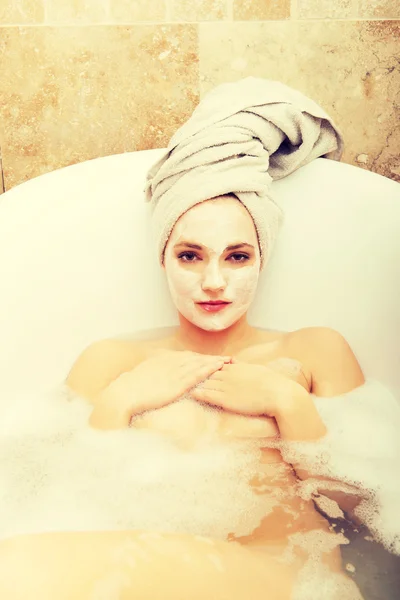 Woman relaxing in bathtub with face mask. — Stock Photo, Image
