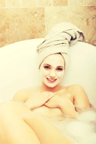 Woman relaxing in bathtub with face mask. — Stock Photo, Image