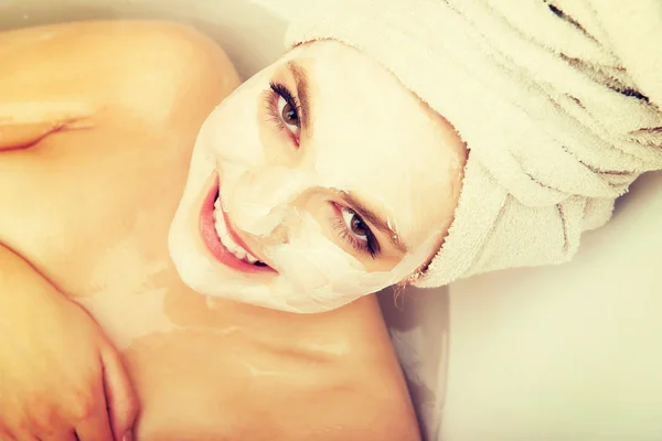 Woman relaxing in bathtub with face mask. — Stock Photo, Image