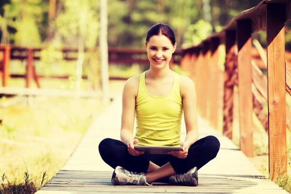 Mulher surfando em tablet depois de correr — Fotografia de Stock