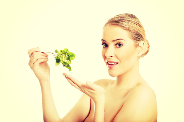 Nude woman eating lettuce