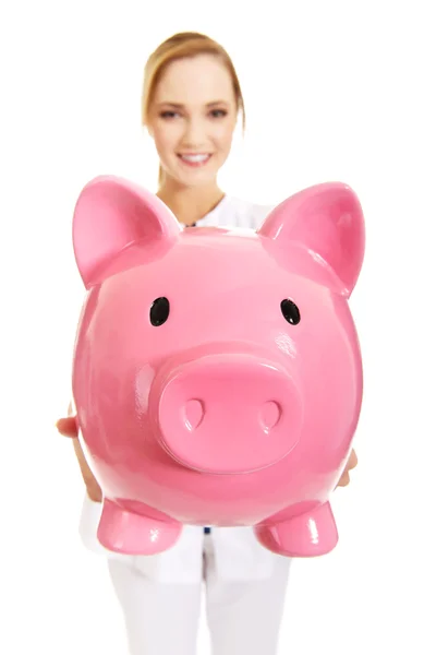 Female doctor holding a piggybank. — Stock Photo, Image