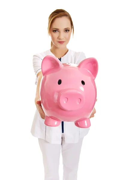Female doctor holding a piggybank. — Stock Photo, Image