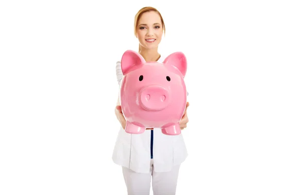 Female doctor holding a piggybank. — Stock Photo, Image