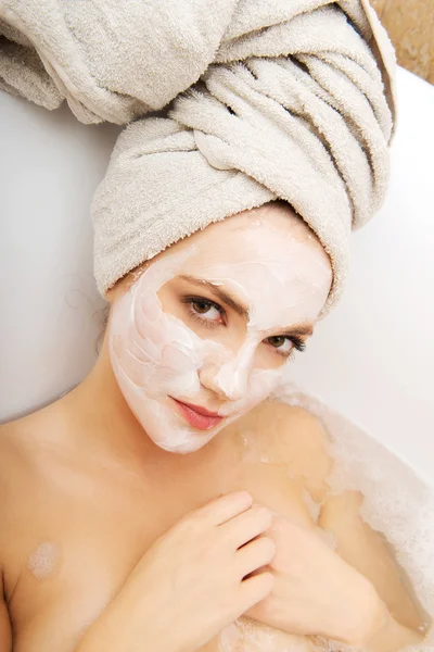 Frau entspannt sich in Badewanne mit Gesichtsmaske. — Stockfoto