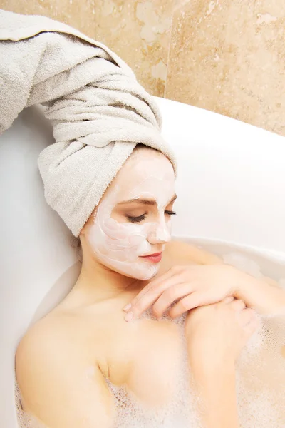 Mujer relajante en bañera con mascarilla facial . —  Fotos de Stock