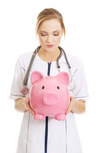 Doctor holding a piggybank. — Stock Photo, Image