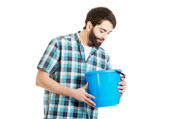 Handsome man looking into plastic bucket. — Stock Photo, Image