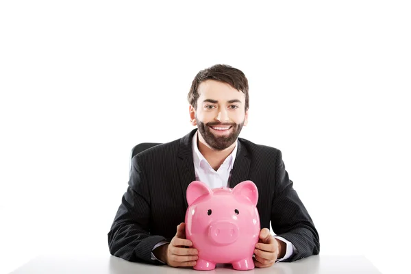 Businessman with piggybank by a desk. — Stock Photo, Image