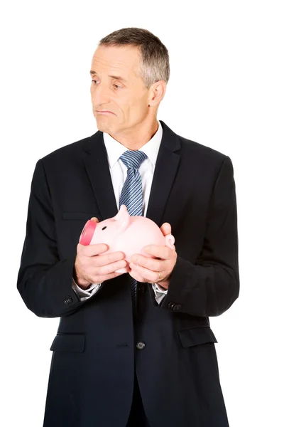 Confused businessman holding piggybank — Stock Photo, Image