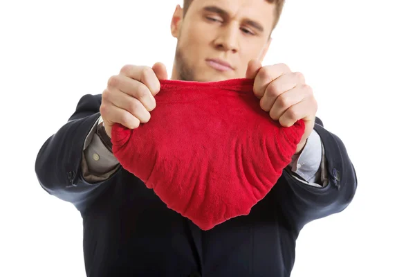 Empresário rasga travesseiro em forma de coração . — Fotografia de Stock