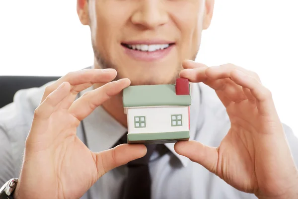 Homme d'affaires avec modèle de maison par un bureau . — Photo