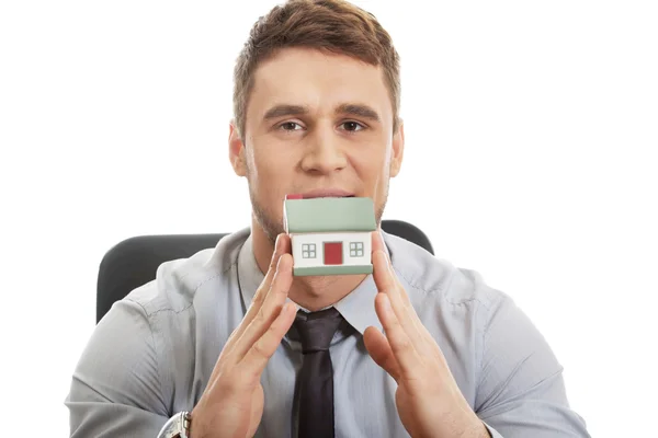 Businessman with house model by a desk. — Stock Photo, Image