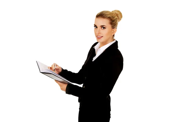 Young businessoman holding notebook and writes something — Stock Photo, Image