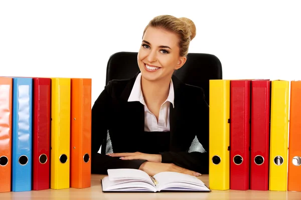 Lächelnde Geschäftsfrau mit Ordnern am Schreibtisch — Stockfoto