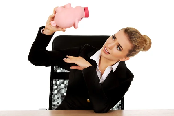 Mujer de negocios preocupada con una alcancía detrás del escritorio — Foto de Stock