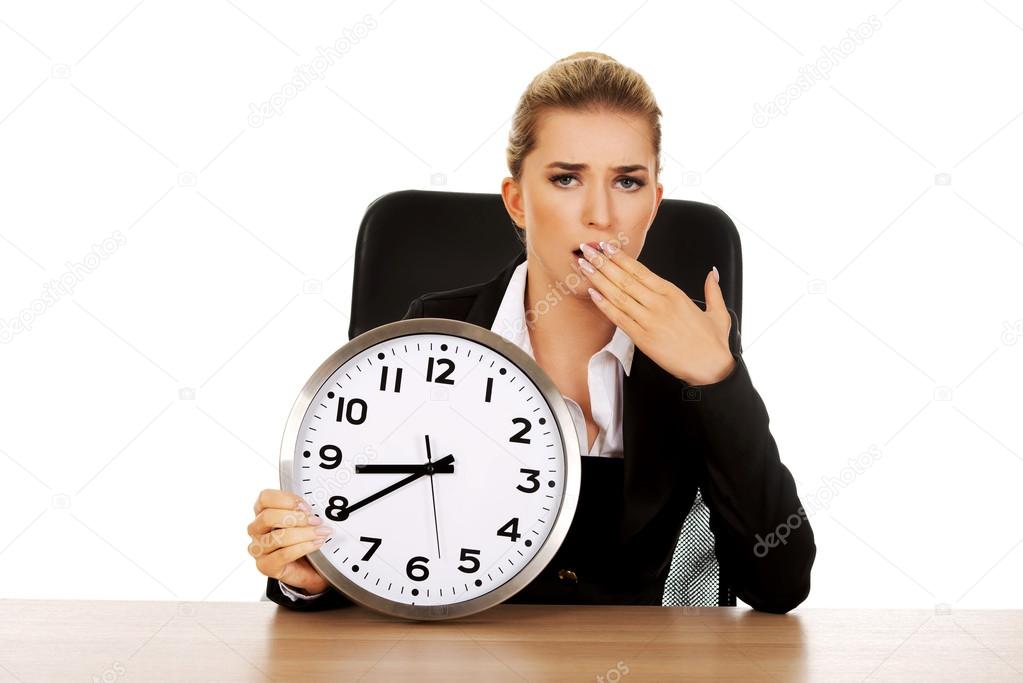 Yawning businesswoman with a clock