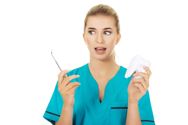 Shocked female denist holding a mirror and tooth model — Stock Photo, Image