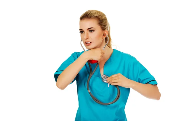 Молода медсестра або жінка-лікар слухати власне серце — стокове фото