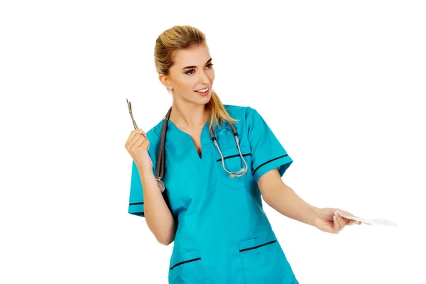 Female nurse holding gauze and scissors — Stock Photo, Image