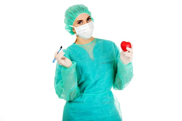 Jonge vrouwelijke cardioloog surgeron holding hart en scalpel — Stockfoto