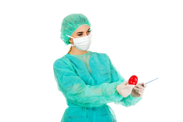 年轻女性心脏病学家 surgeron 持有的心和手术刀 — 图库照片