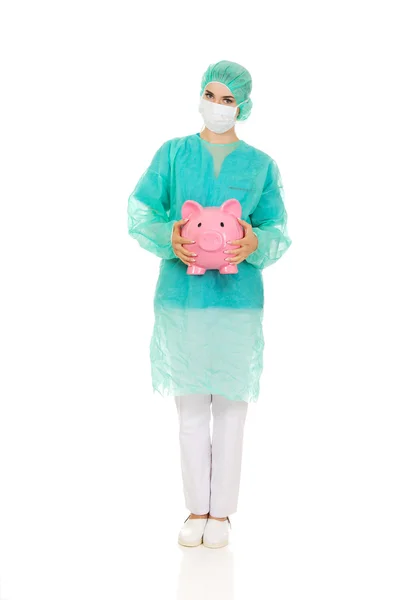 돼지 저금통을 들고 여성 외과 의사 — 스톡 사진