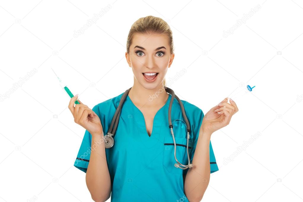 Suprised female nurse with two syringes in the hands