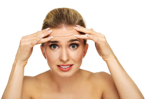 A young woman checking wrinkles on her forehead — Stock Photo, Image