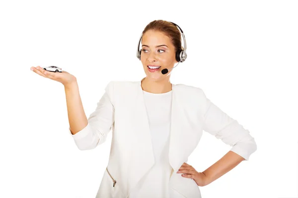 Young businesswoman in headset holding car toy — Stock Photo, Image