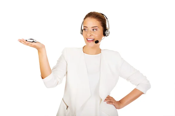 Joven mujer de negocios en auriculares sosteniendo juguete de coche —  Fotos de Stock